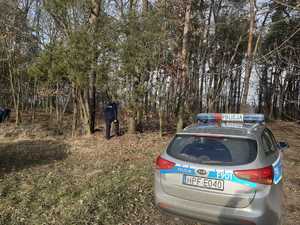 Policjanci podczas działań poszukiwawczych. Na pierwszym planie radiowóz.