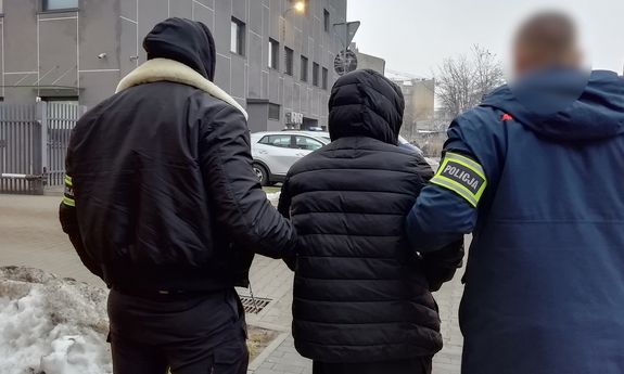 Dwaj nieumundurowani policjanci prowadzą zatrzymanego.