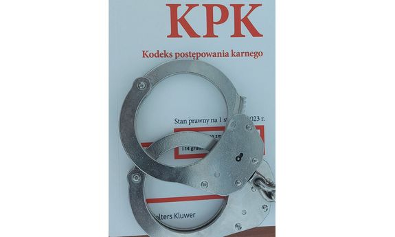 Na zdjęciu kodeks postępowania karnego, na nim leżą policyjne kajdanki.
