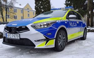 Radiowóz na śniegu przed komendą.