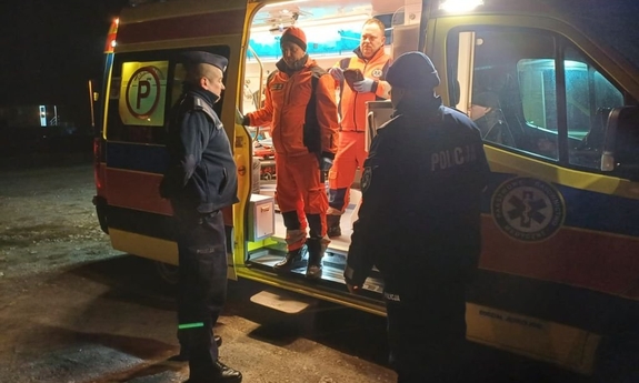 Policjanci i załoga pogotowia przy karetce.