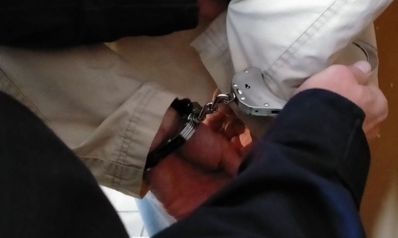 Zatrzymany, który ma założone kajdanki.