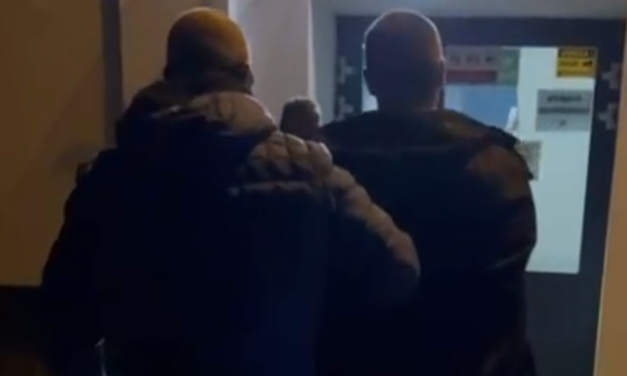 Policjant prowadzi zatrzymanego mężczyznę.