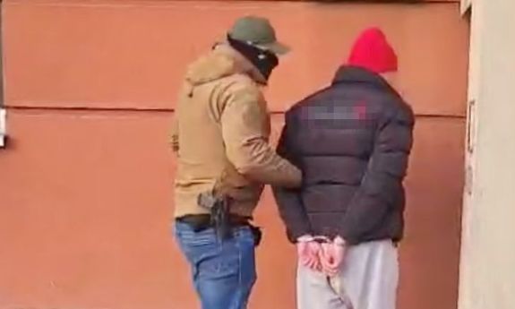 policjant idzie z zatrzymanym.