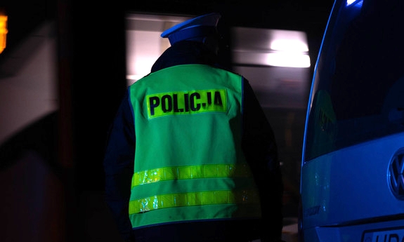 Funkcjonariusz przy pojeździe w trakcie kontroli. Pora nocna.
