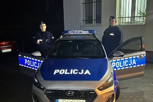 dwóch policjantów stojących po obu stronach radiowozu