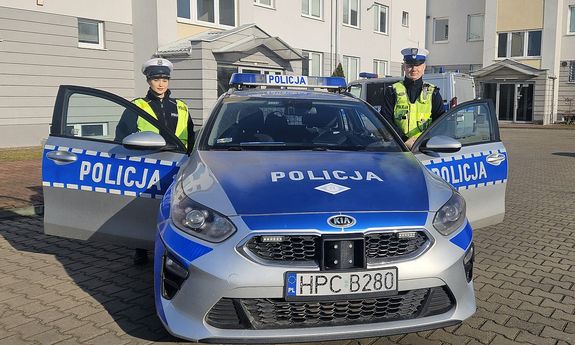 Patrol umundurowanych policjantów przy radiowozie. Na zdjęciu sierż. szt. Wojciech Krajewski i post. Milena Gizela. W tle widać budynek.