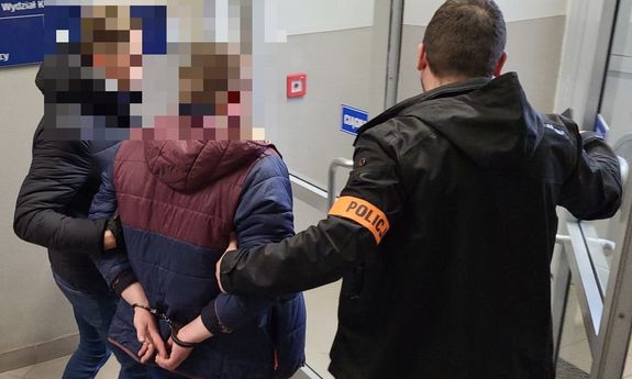 policjanci z zatrzymanym. jeden z policjantów otwiera drzwi.