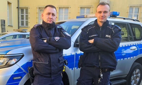 policjanci stoją przed radiowozem