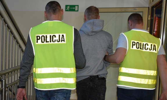 Dwaj policjanci prowadza zatrzymanego.