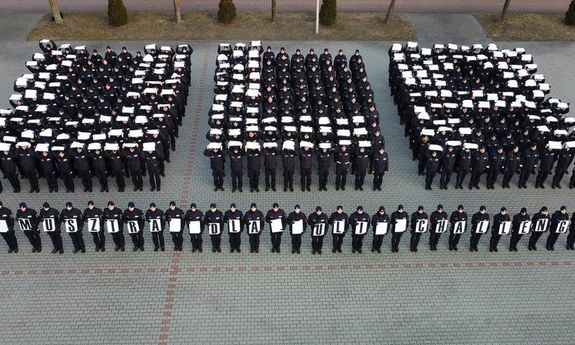 policjanci układają napis ULA z białych kartek.