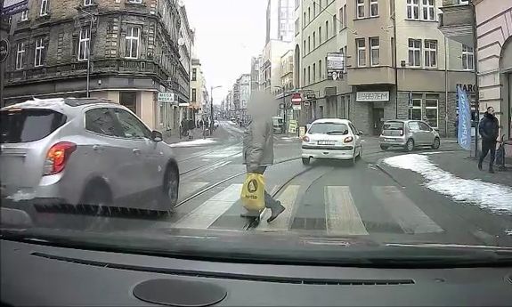 kadr z kamerki samochodowej. Auto przejeżdża przed pieszym.