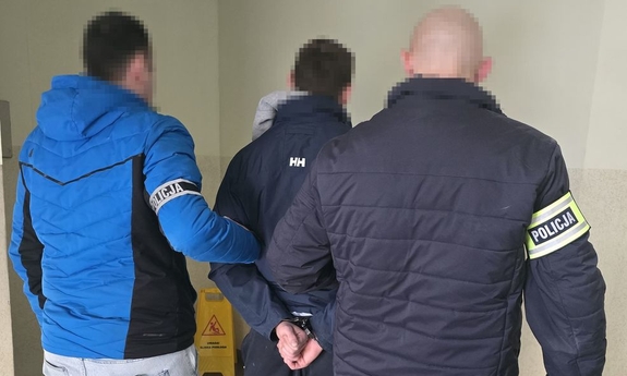 Dwaj funkcjonariusze prowadzą zatrzymanego.