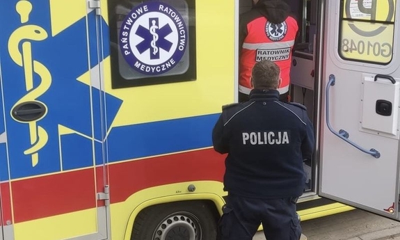 Policjant i ratownik medyczny przy karetce.