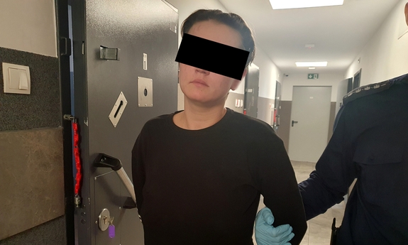 Na zdjęciu policjant prowadzi zatrzymaną kobietę.