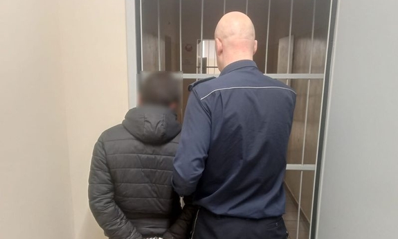 Policjant z zatrzymanym przy kratach.