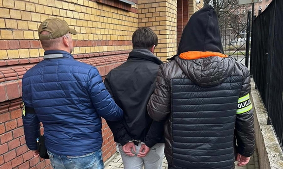 Funkcjonariusze prowadzą zatrzymaną osobę.