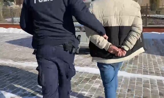 policjant idzie z zatrzymanym.