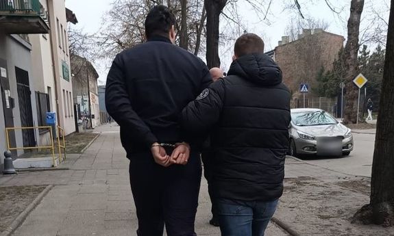 policjant idzie z zatrzymanym.