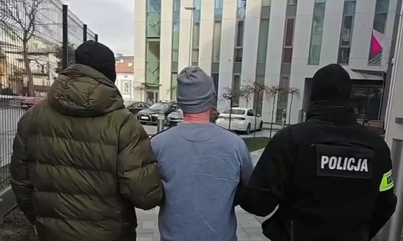Dwaj funkcjonariusze prowadzą zatrzymanego.