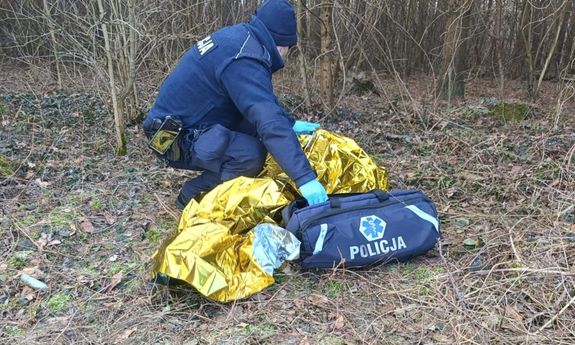 las, policjant udziela pomocy poszkodowanemu.