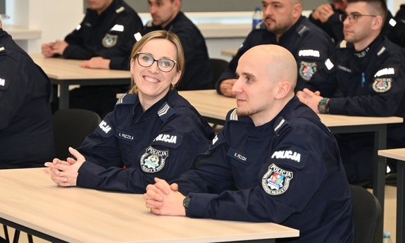 Policjanci siedzą na sali w ławkach podczas kursu.
