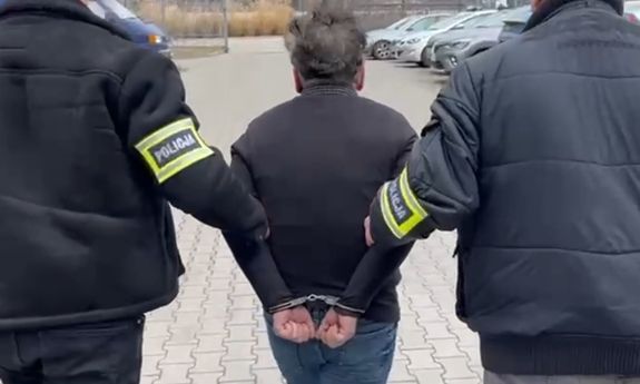 dwóch policjantów idzie z zatrzymanym.