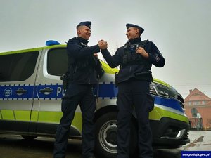 Od lewej sierż. Daniel Gburzyński i sierż. Andrzej Przybyłowski stoją przy radiowozie.
