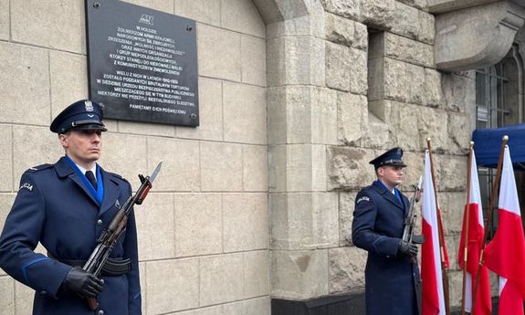 Policjanci przed tablicą upamiętniająca żołnierzy wyklętych