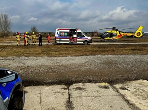 Funkcjonariusze różnych służb stoją przy karetce pogotowia, a obok widać śmigłowiec Lotniczego Pogotowia Ratunkowego.