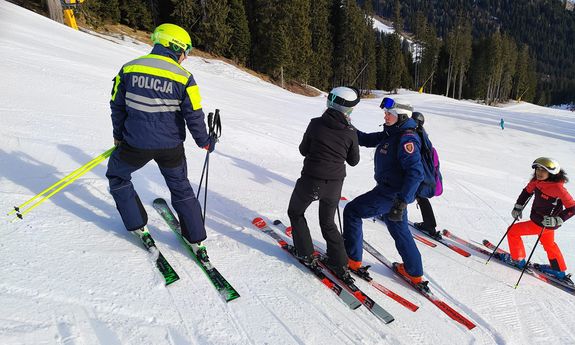 Polski i włoski policjant podczas rozmowy z narciarzami na soku.