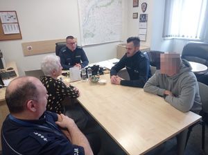 policjanci i zaproszona kobieta siedzą przy stole.