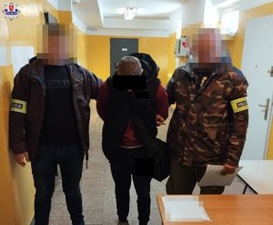 Dwaj funkcjonariusze prowadzą zatrzymanego.