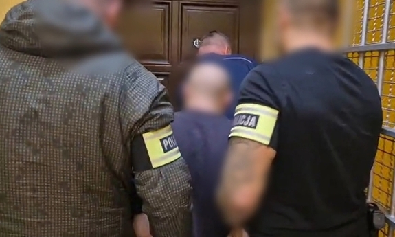 Dwaj policjanci prowadza zatrzymanego.