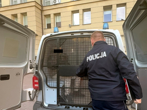 Policjant stoi przy radiowozie typu bus.