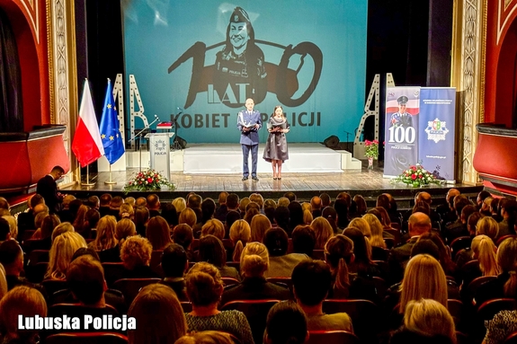 Wnętrze teatru - widownia i scena na której stoją konferansjerzy.