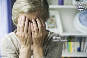 Starsza Pani zasłaniająca dłońmi twarz. W prawy górnym rogu widoczna jest policyjna gwiazda z napisem Policja Głubczyce, a wokół niej napis: Pomagamy i chronimy.
