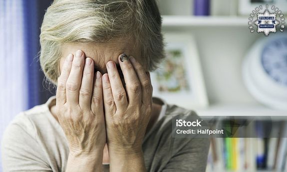 Starsza Pani zasłaniająca dłońmi twarz. W prawy górnym rogu widoczna jest policyjna gwiazda z napisem Policja Głubczyce, a wokół niej napis: Pomagamy i chronimy.