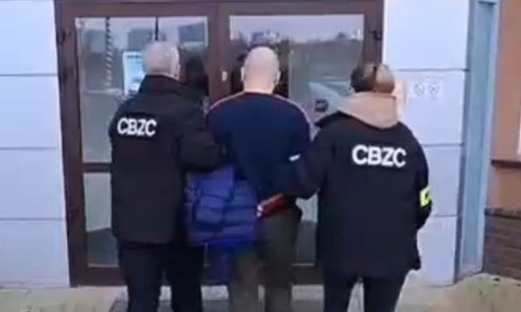 Dwaj funkcjonariusze prowadza zatrzymanego.