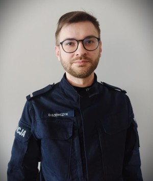 Umundurowany policjant pozuje do zdjęcia.