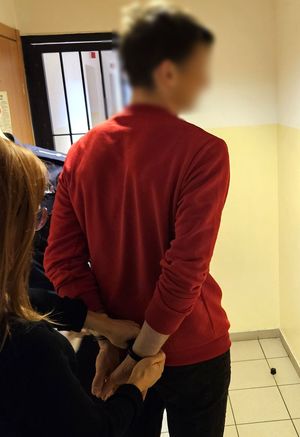 Zatrzymany mężczyzna podczas przesłuchania. Na rękach ma założone kajdanki.