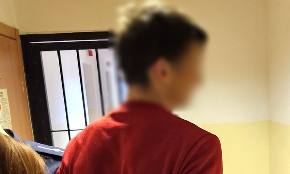 Zatrzymany mężczyzna podczas przesłuchania. Na rękach ma założone kajdanki.