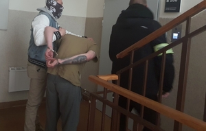 Policjanci z zatrzymanym zakutym w kajdanki.