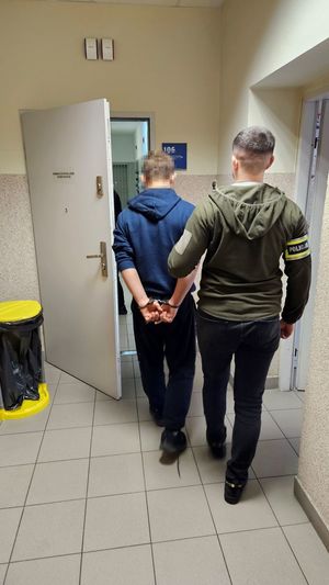 Dwaj funkcjonariusze prowadzą zatrzymanego.