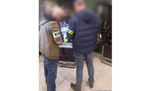 Policjant i funkcjonariusz służby celnej przy maszynie do gier.