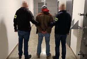 Dwaj ubrani po cywilnemu policjanci z zatrzymanym.