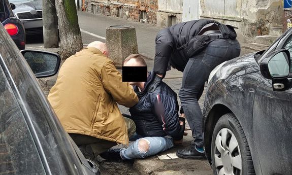 dwóch policjantów zatrzymało mężczyznę na chodniku.