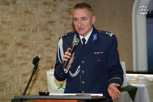 Umundurowany policjant przemawia stojąc przy mównicy.