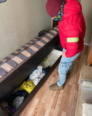 Zabezpieczone narkotyki w tapczanie. Obok stoi policjant.
