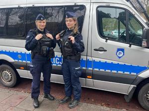 Dwie umundurowane policjantki przed policyjnym furgonem.